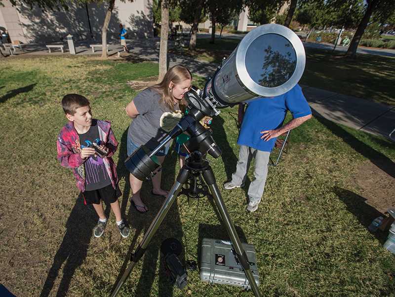 Brooke Dressel and her son Riley Dressel view the solar eclipse through a telescope set up by a member of the Central Valley Astronomers, outside of the Downing Planetarium, Thursday, Oct. 23, 2014.