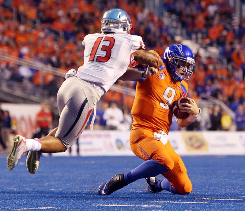 Boise State quarterback Grant Hedrick (9) absorbs a hit from Fresno State safety Derron Smith (13) in the first half at Albertsons Stadium in Boise, Idaho, on Friday, Oct. 17, 2014. (Darin Oswald/Idaho Statesman/Tribune News Service)