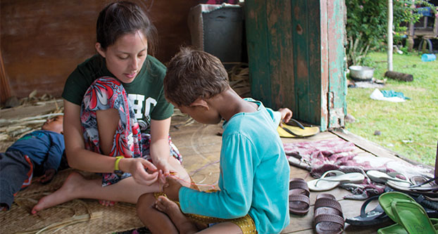 Fresno State student Cassie Niino (left) teaches Snow (right) how to make a friendship bracelet in Naboutini, Fiji on Jan. 5, 2015. Niino was one of many students who participated in a service-learning trip put on by the Jan and Bud Richter Center for Community Engagement and Service-Learning and Madventurer during winter break. (Yvette Mancilla/The Collegian)