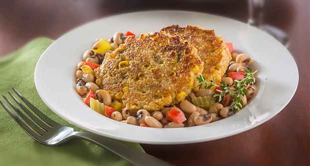 A stew of black-eyed peas and sautÃ©ed vegetables is topped with pan-fried corn cakes, a recipe from “Vegetarian Dinner Parties.” Food styling by Corrine Kozlak. (Bill Hogan ”¢ Chicago Tribune/TNS)