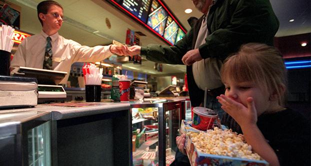 Sidney Williams, 5, dug into her popcorn this week at the UA MacArthur Marketplace 16 in Irving, Texas, while her grandfather Gary Williams paid the bill. (Mona Reeder/Dallas Morning News/TNS)
