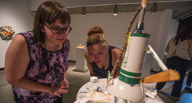 Interior design students Carly Grote and Sarah Anderson admire the intricacy of the brushes from Richard Shaw’s ceramic piece “Tabouret with Figure” during the “Still Life in Ceramics” reception in the Conley Art Gallery, Thursday, Sept. 10, 2015. The exhibition displays the art of five Bay Area artists invited by Una Mjurka, assistant professor in the Department of Art and Design. The show will run until Sept. 17. (Darlene Wendels/The Collegian)