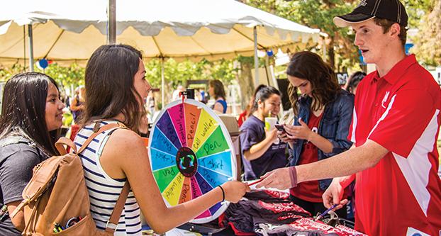 Students crowd around the ASI booth during the community service opportunities fair, Sep. 2, 2015. Students got to spin the wheel for their chance to win a prize. 