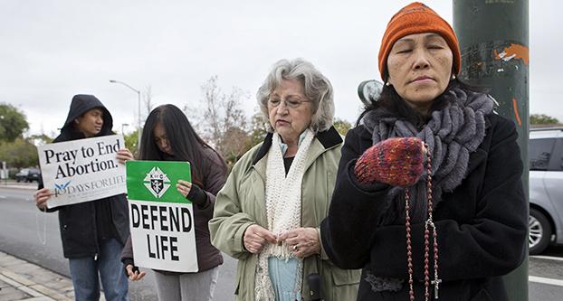 Hang Nguyen of Santa Clara, right, Kathy Doerr, of Mountain View, center right, Ramil Batiancila, left, and Bernadette Batiancila, both of Fremont, pray in protest against abortion in front of the Planned Parenthood Health Center in Mountain View, Calif., Feb. 6, 2014. (LiPo Ching/Bay Area News Group/TNS)