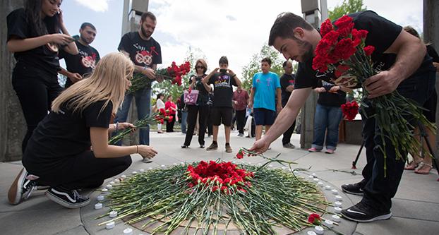 Tadeh Issakhanian and other attendees of the 101st anniversary of the Armenian Genocide place carnations in the center of the Armenian Genocide Monument at Fresno State, Friday, April 22, 2016. (Darlene Wendels/The Collegian)