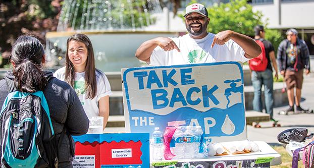 Nicole Lucha (left) and Anthony Anderson (right) tests students on whether or not they know the difference between tap water and bottled water, at the Earth Day event in the memorial garden. (Khone Saysamongdy/The Collegian)
