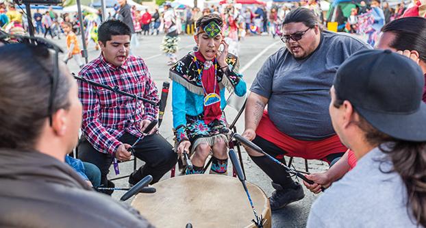 Native American Indian music group Blood River, beats the drum while performers dance in the background during the 25th Annual First Nations Powwow event in P-Lot 20, April 9, 2016. The group sings in a high pitch voice to mimic the sound of an eagle. (Khone Saysamongdy/The Collegian)