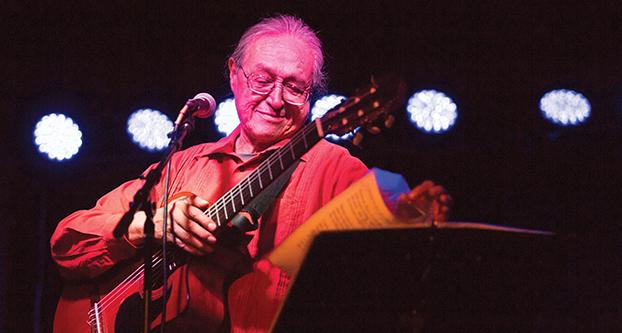 Gabino Palomares performs at Fulton 55 on Oct. 5, 2016. Palomares flips through his songbook to pick the next song to perform. (Christian Ortuno/The Collegian)