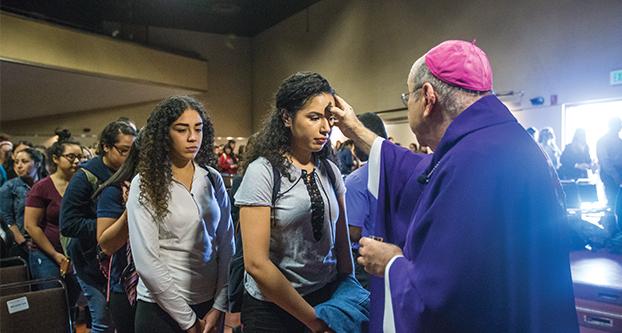 Bishop Armando Ochoa ashes the foreheads of the Fresno State community in the Satellite Student Union on March 1, 2017.  The markings represent the start of the Season of Lent. (Khone Saysamongy/The Collegian)