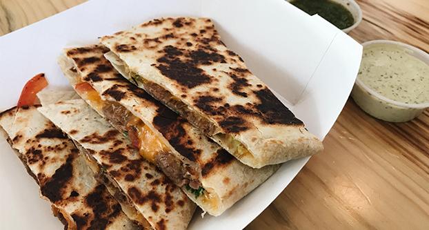 A shredded beef quesadilla with cheddar cheese, tomato and cilantro, with two of Quesadilla Gorilla’s seven homemade salsas on the side. (Selina Falcon/The Collegian)