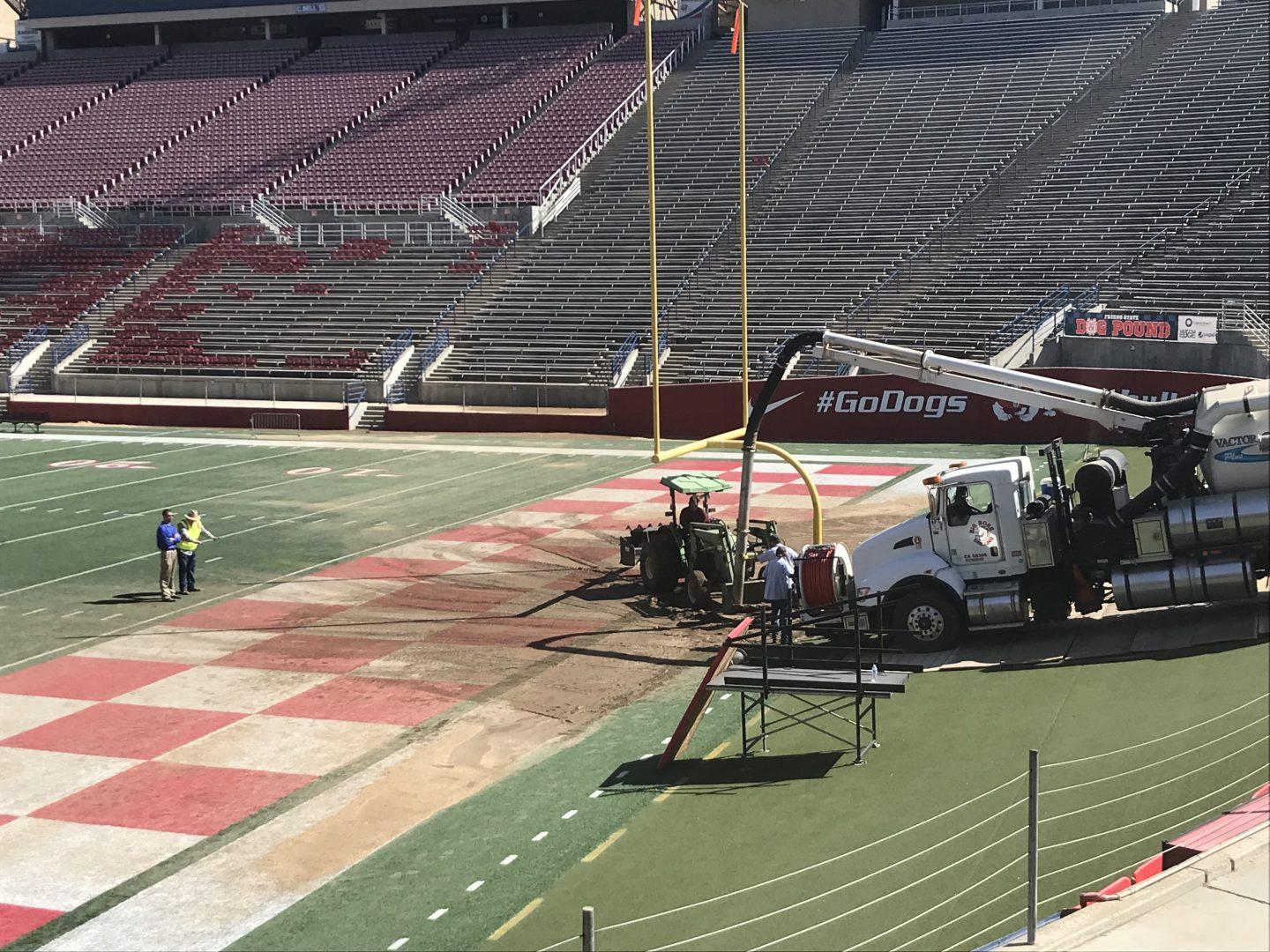 Workers cleaning up mud and debris on the south end zone at Bulldog Stadium on Sept. 25, 2017. (Daniel Gligich/The Collegian)