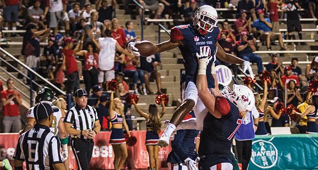 Senior Fresno State center Aaron Mitchell (77) holds up wide receiver KeeSean Johnson (3) after the receiver scored a touchdown against Sacramento State on Sept. 10, 2016 at Bulldog Stadium. Fresno State won 31-3. (Collegian File Photo) 