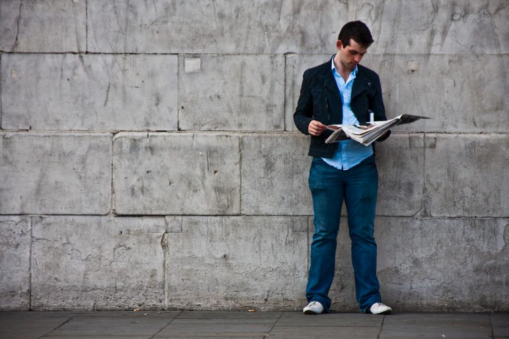 A man reads a newspaper by the wall. 
Photo Courtesy: Flickr