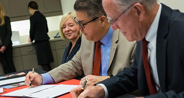 Fresno State President Joseph Castro and San Joaquin Memorial High School Principal Tom Spencer sign the Memorandum of Understanding during the signing ceremony in the Smittcamp Alumni House on March 5, 2018. The memorandum pledges to offer SJMHS students a direct pathway to Fresno State if students fulfill certain requirements. (Ram Reyes/The Collegian)