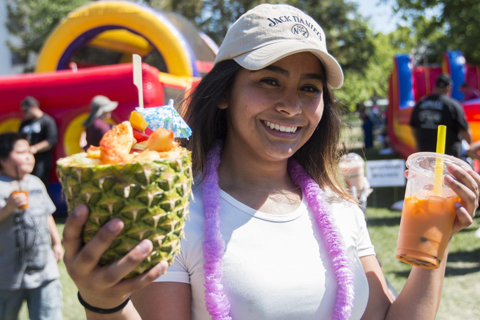 Angela Perez holds a Fineapple on her right hand sold at the International Student Association booth at Vintage Days on April 22, 2018. (Ramuel Reyes/The Collegian)