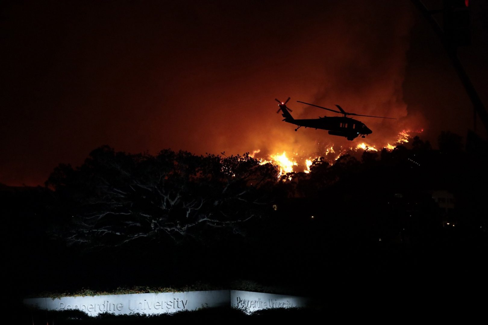 A helicopter battle the Woolsey wild fire in the hills above Pepperdine University in Malibu, Friday, November 9, 2018. (Calvin Alagot/Los Angeles Times/TNS)