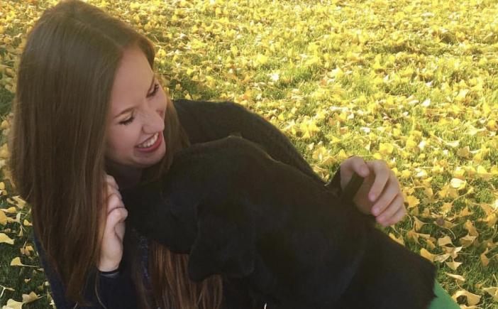 Caitline Hoover plays with Wheaton, a chocolate Labrador that she trains. 