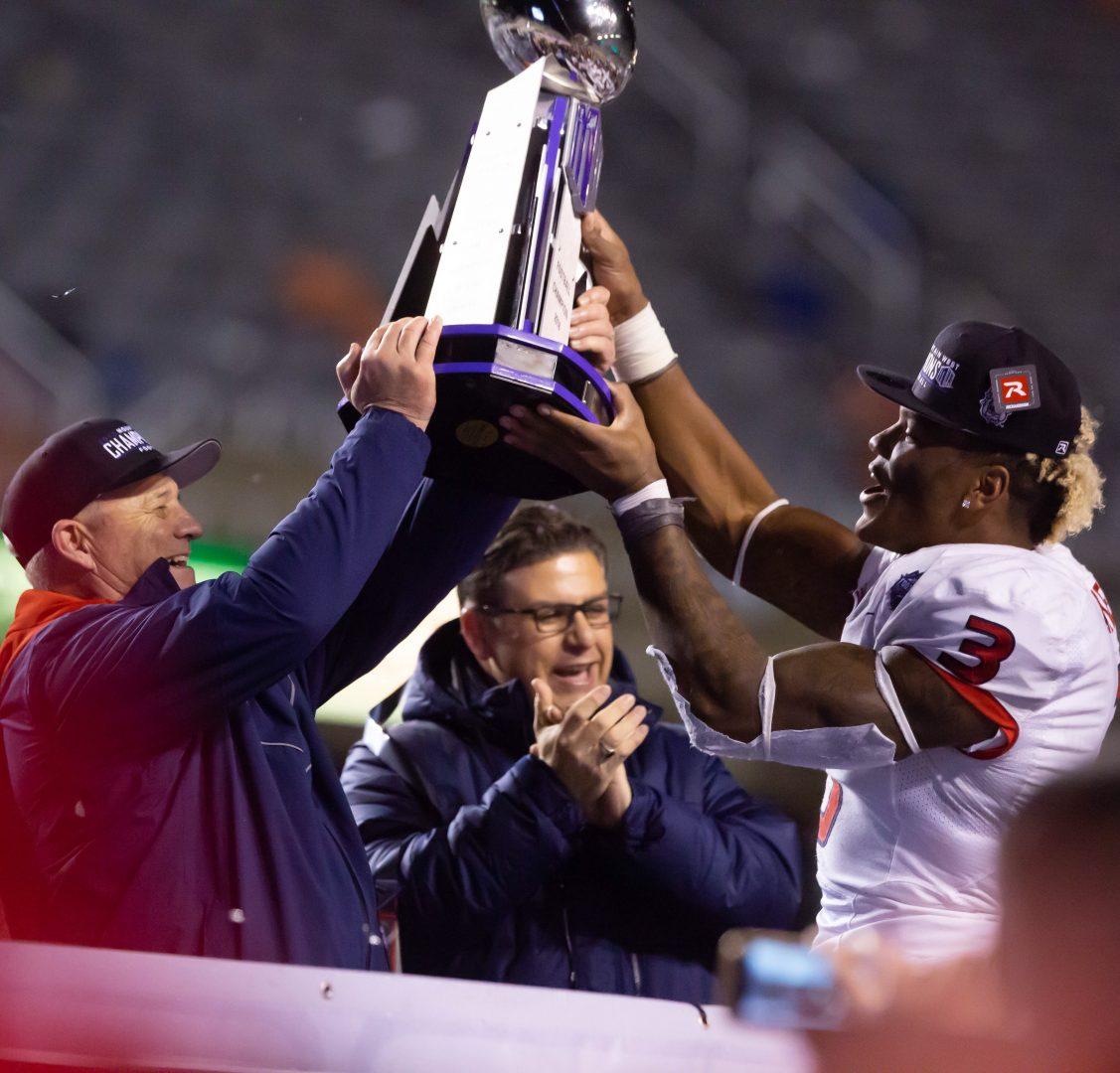 Fresno+State+defensive+end+Mykal+Walker+holds+the+Mountain+West+Championship+trophy+with+head+coach+Jeff+Tedford+as+President+Dr.+Joseph+Castro+cheers%2C+following+the+Dogs+win+over+Boise+on+the+blue+turf.+%28Jose+Romo%2FThe+Collegian%29
