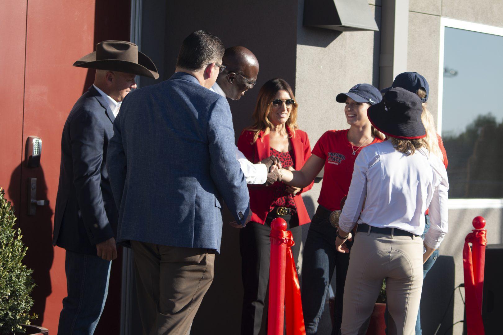 Fresno State equestrian team captains shake hands with the Director of Athletics Terry Tumey and University President Doctor Joseph I. Castro after the cutting of the ribbon for their new Equestrian Center grand opening at the Student Horse Center on Friday, Oct. 25, 2019.
