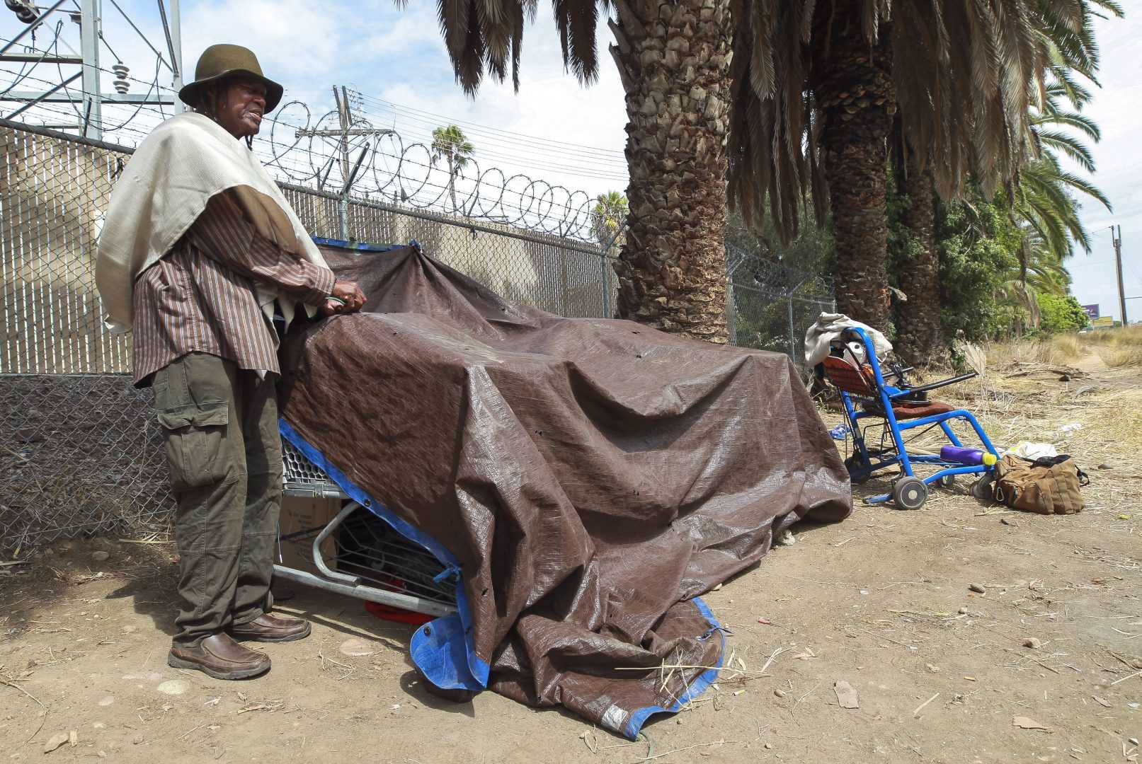 Charles Patterson, 69, who says hes been homeless for five years, ties down a tarp at his encampment that is nearby the proposed storage area site for homeless peoples belongings, located next to Chollas Parkway, on Wednesday, September 25, 2019 in San Diego, California. Patterson said he would use the storage site if he could be reassured that his belongings would be safe there.
