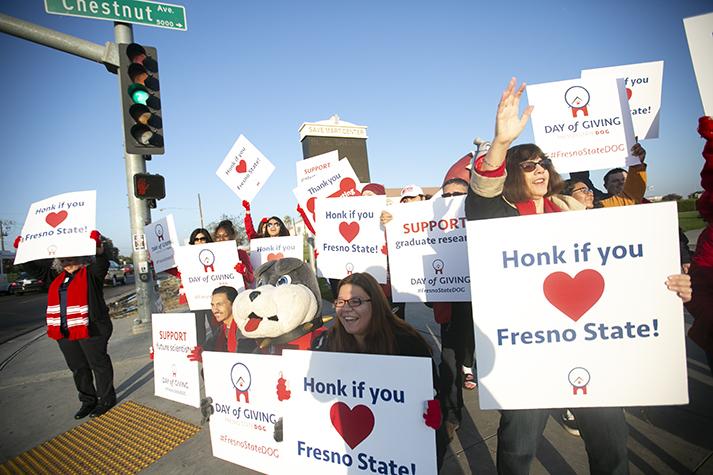 Students, faculty and staff and mascot TimeOut cheer in front of passing traffic to promote Day of Giving in front of the Save Mart Center on Nov. 7, 2019. The fundraiser brought in a total of $550,366 from 2,161 individual donors, according to preliminary estimates. (Larry Valenzuela/The Collegian)