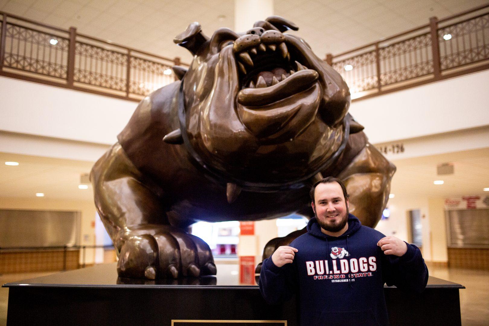 Elliot Meme, superfan, stands in front of the bronze Bulldog statue at the Save Mart Center on Tuesday, Feb. 4, 2020. (Armando Carreno/The Collegian)
