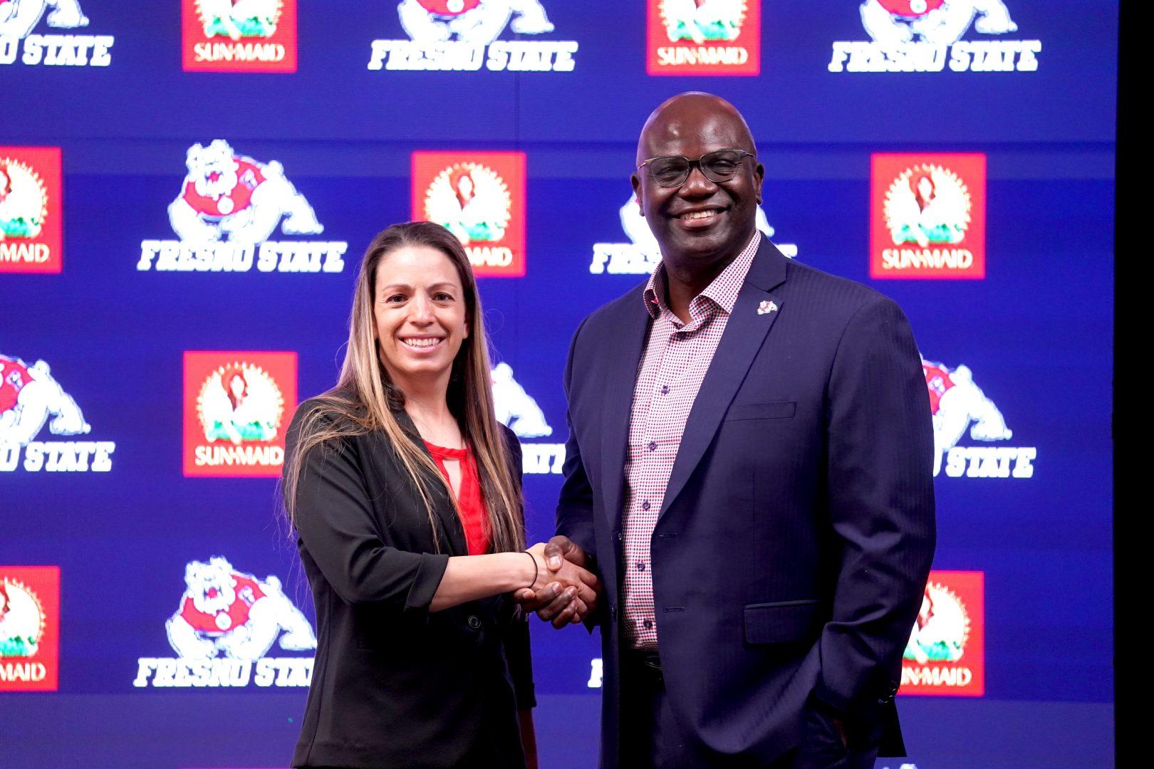 Stacy May-Johnson (left) shakes hands with Fresno State athletic director Terry Tumey (right) at a news conference on July 6. (Courtesy of Fresno State Athletics)