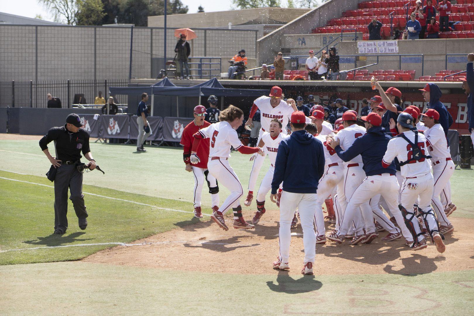 The Fresno State Baseball team celebrated as Senior Josh Lauck runs home after hitting the game winning home-run in the second game of the series against Nevada on March 20, 2022. (Wyatt Bible/ The Collegian)
