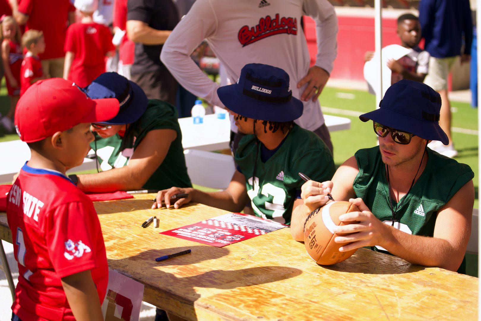 Fresno State Quarterback Jake Haener signs a football for a fan for Fan Appreciation Day on Aug 21, 2022, at Valley Childrens Stadium. (Blake Wolf/ The Collegian)