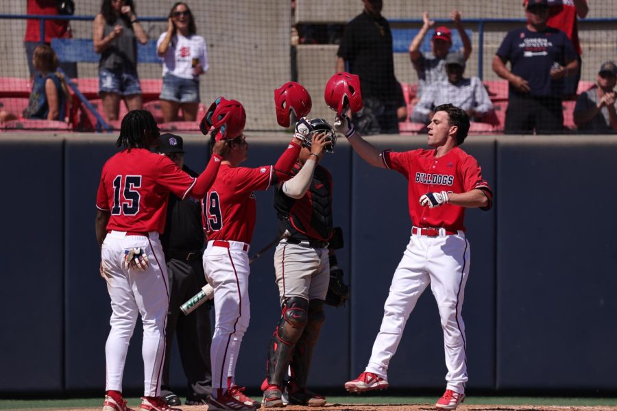 Fresno State baseball players celebrate at home plate after a 3-run home run. 