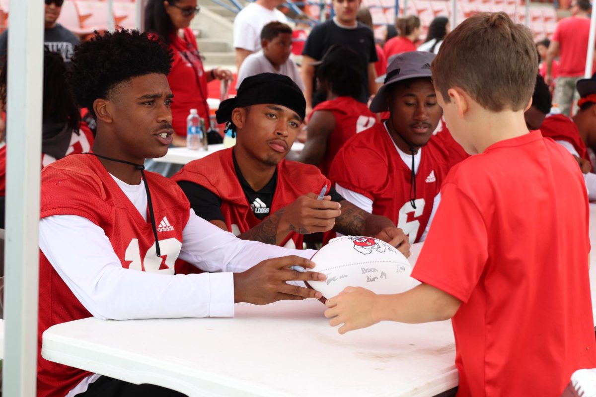 Wide receivers Jalen Moss and Nathan Acevedo sign a Fresno State football for a young fan at the Fan Appreciation Day event on Aug. 20. 