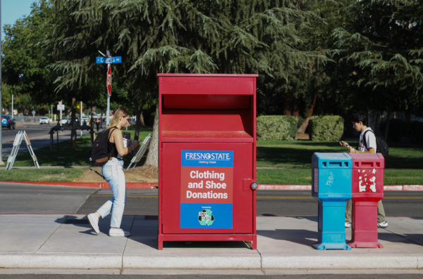 Fresno State students walking past a clothing and shoe donation bin near parking lot P20. (Carlos Rene Castro/ The Collegian)