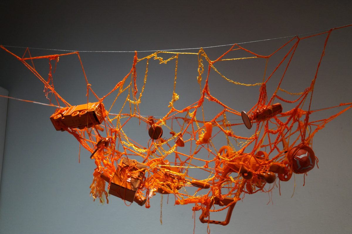 Strident+Song+by+Liliana+Pantoja+displays+a+jumble+of+orange+objects+entangled+in+yarn.