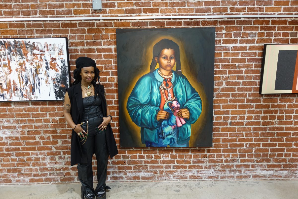Audia Dixon, a Fresno State alum, beside her artwork Little Meghal.