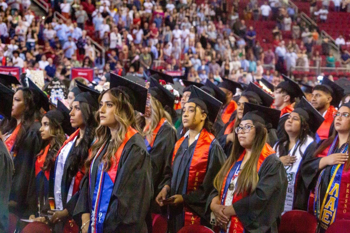 Students standing during the flag salute at the 2023 Fresno State commencement ceremonies.