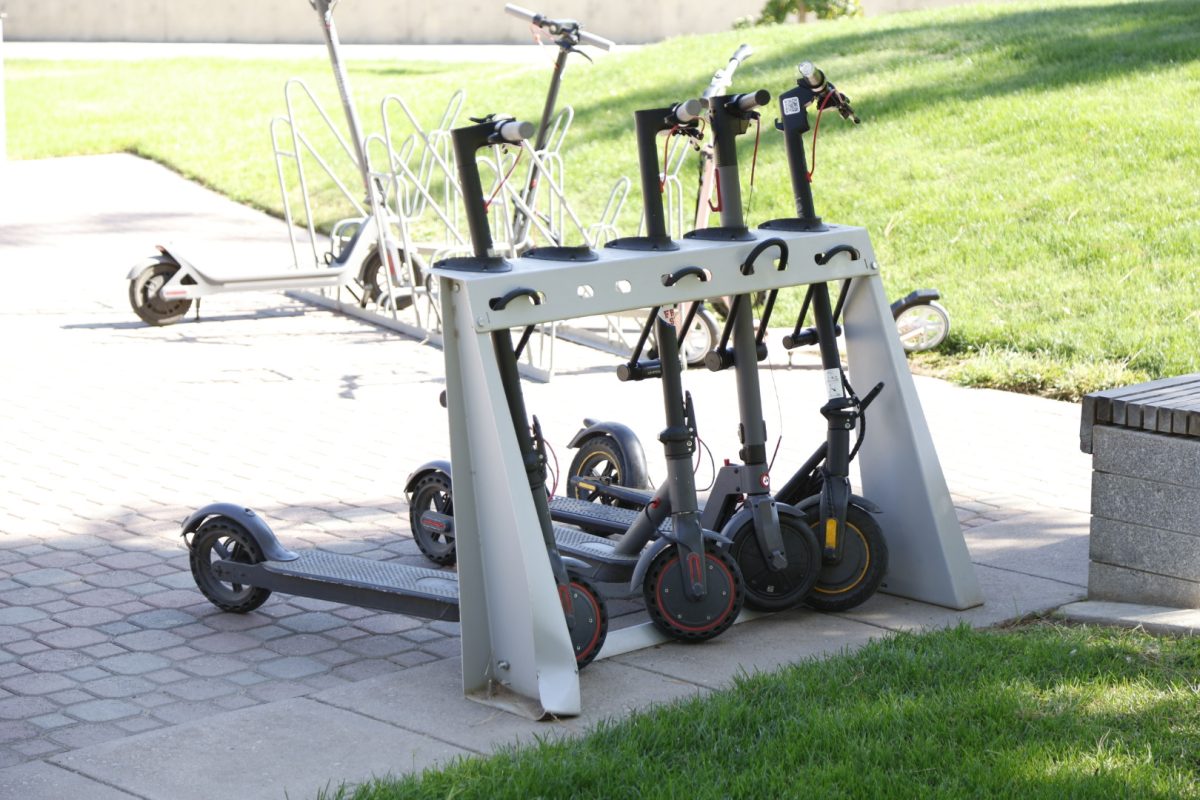 A row of scooters locked in a campus rack.