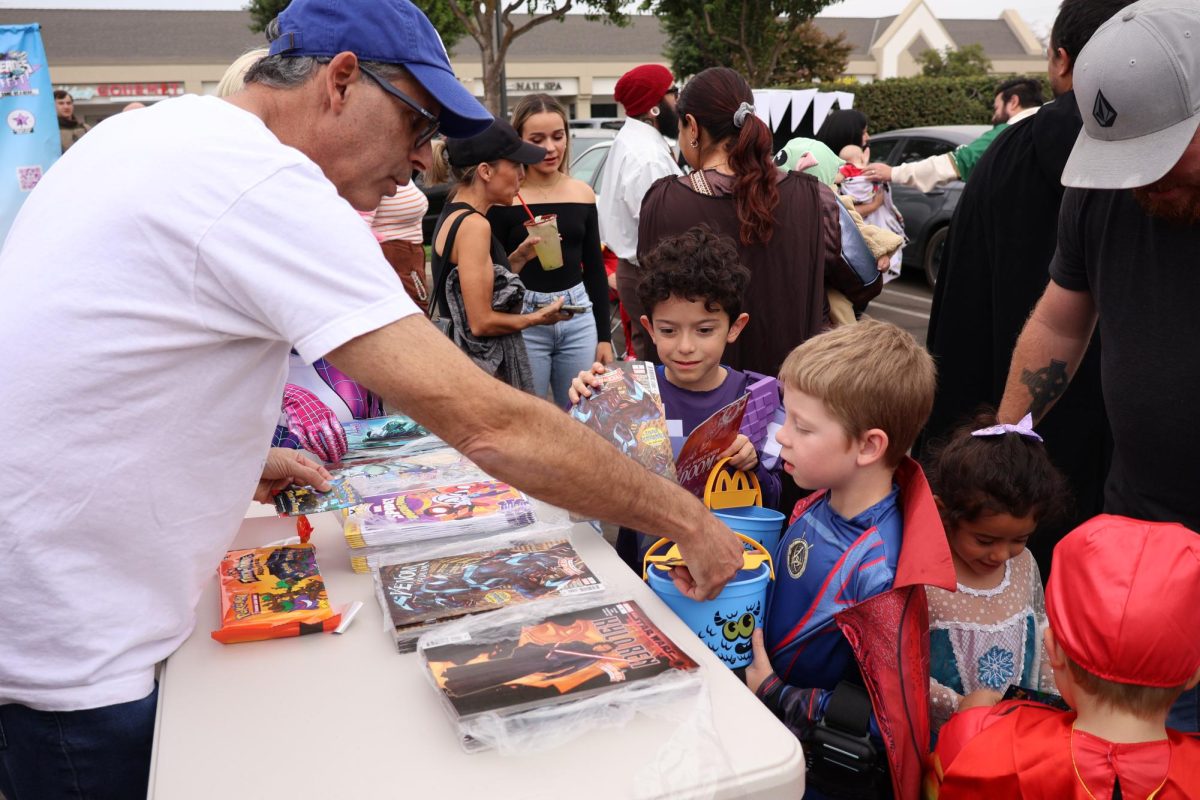 A worker from Secret Identity Comics hands out free comic books and candy to children at Heroes Fest on Sept. 27, 2024.