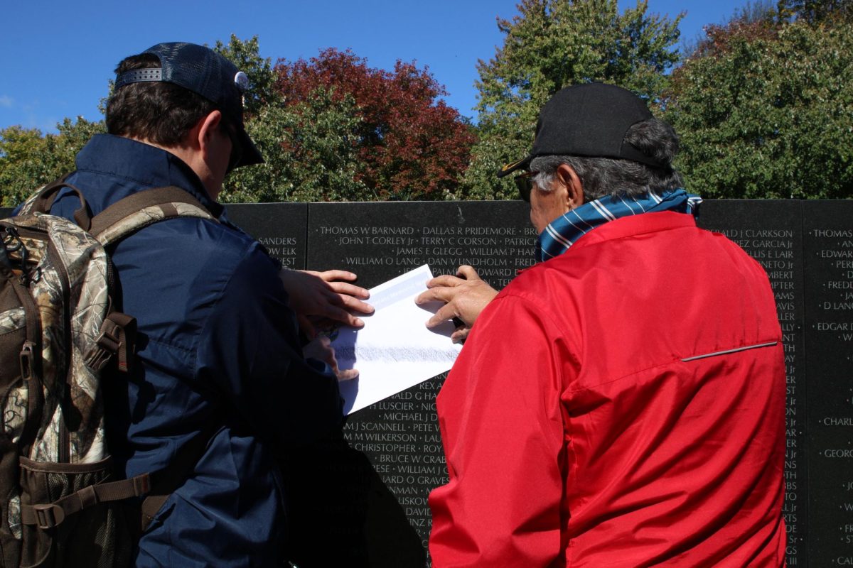 Veteran and guardian chalk name on paper at the Vietnam Wall on Oct. 16.