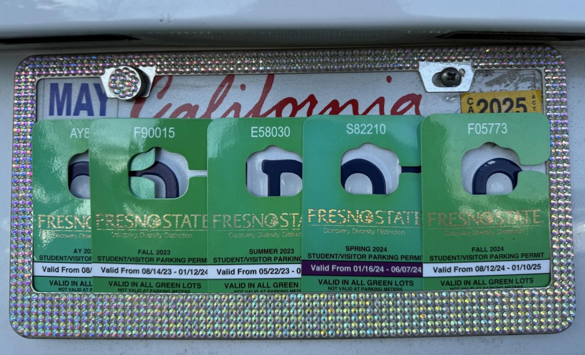 A collection of Fresno State parking permits displayed over a California license plate on Jan. 15. Fresno State's parking permits are now fully digital as of January 2025. 