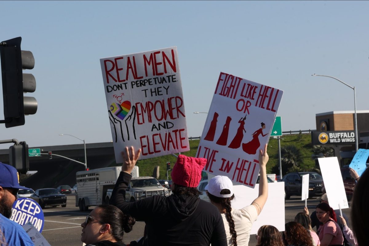 Protesters raise signs for the 2025 People's March outside of the Save Mart Center on Jan. 18.