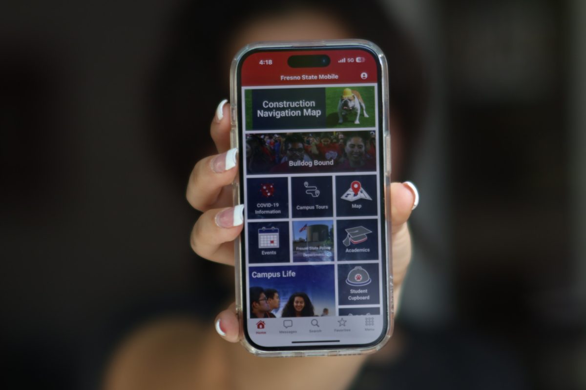 A Fresno State student holds up an iPhone showing the Mobile@FresnoState app homepage on Aug. 27. 