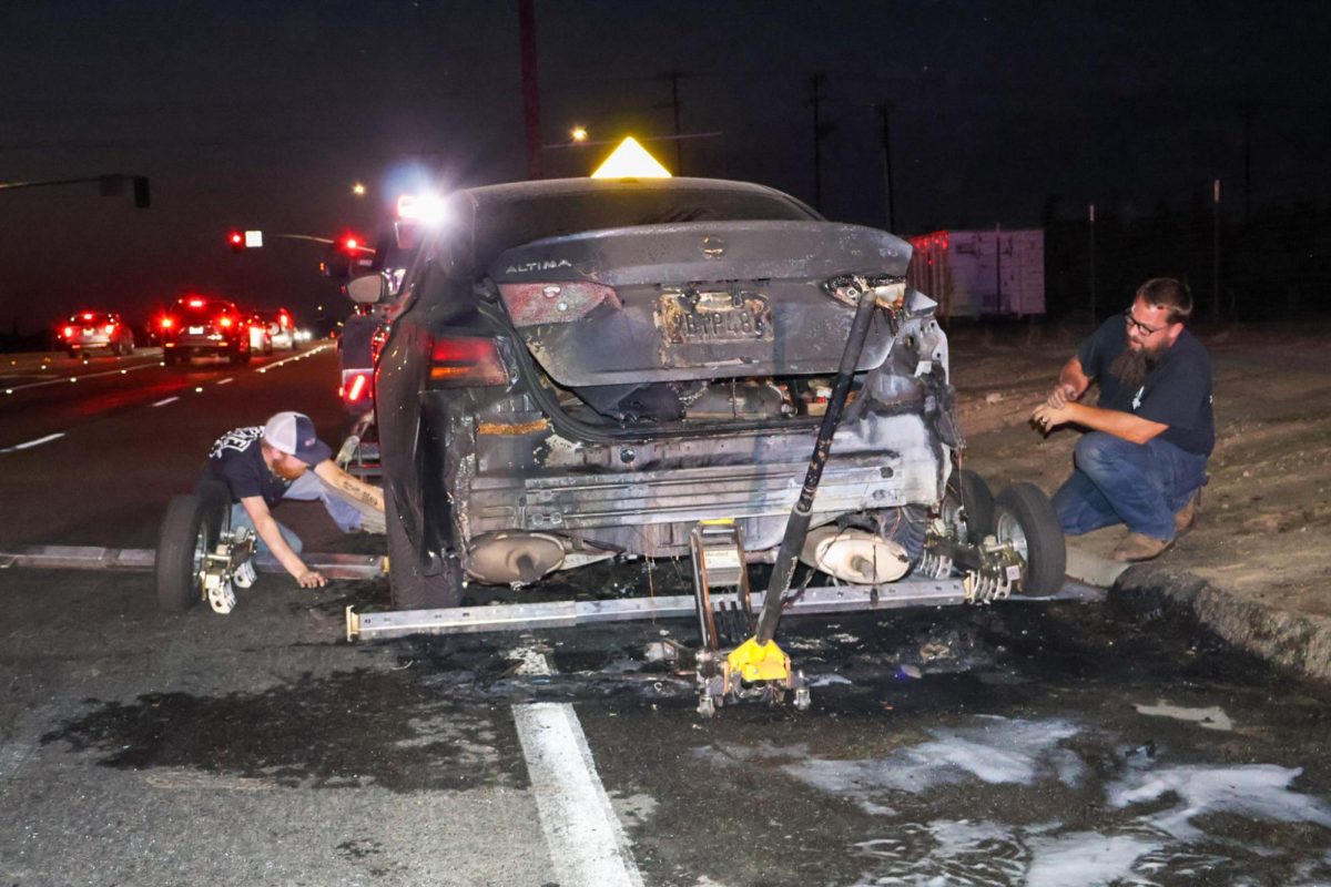 Tow truck drivers secure a Nisan Altima to a tow truck after a vehicle caught fire on Chestnut Avenue and Bulldog Lane on Sept. 12.
