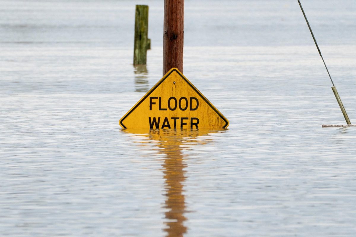 A sign warning drivers about flood water is partially covered by water in an area flooded by the Snohomish River, as an atmospheric river brings rain and flooding to the Pacific Northwest, in Snohomish, Washington, U.S., December 11, 2025. REUTERS/David Ryder