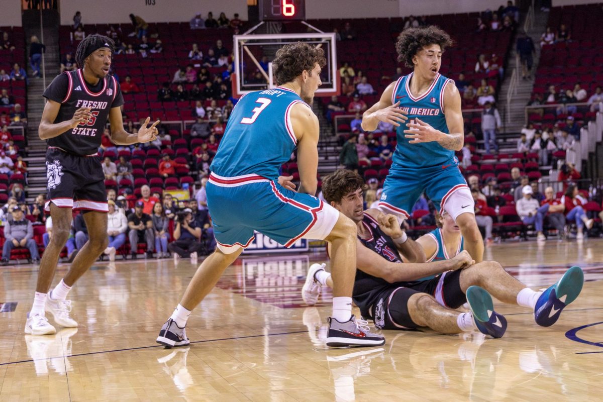 Fresno State men's basketball center Wilson Jacques sits on the ground in between two New Mexico Lobo defenders near on the right wing on Feb. 21 at the Save Mart Center.