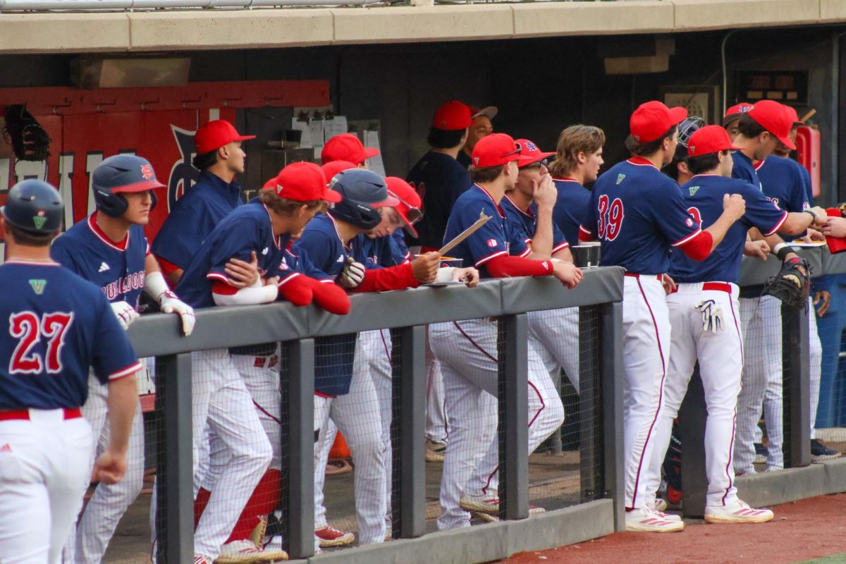 Players lean on the railing of the home dugout of Bob Bennett Stadium on Feb. 14. The Diamond 'Dogs debuted their new blue home jerseys in a 5-4 loss to the Utah Utes.