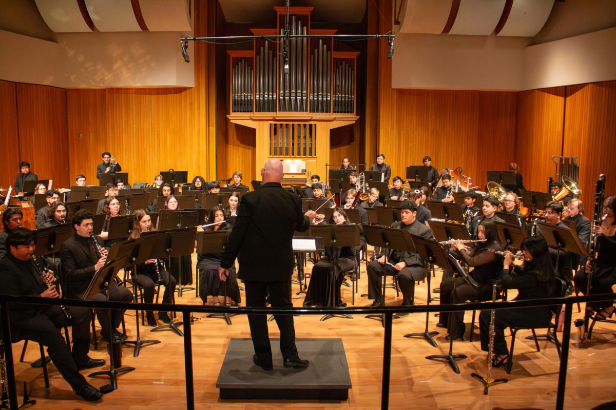 Professor Steve McKeithen is directing the wind orchestra through their 6-piece program inside the Fresno State Concert Hall.