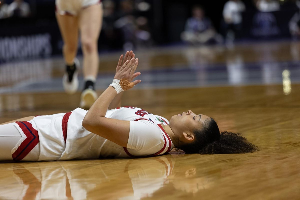 Avery Watkins lays on the hardwood after a foul as her teammates come to support her.