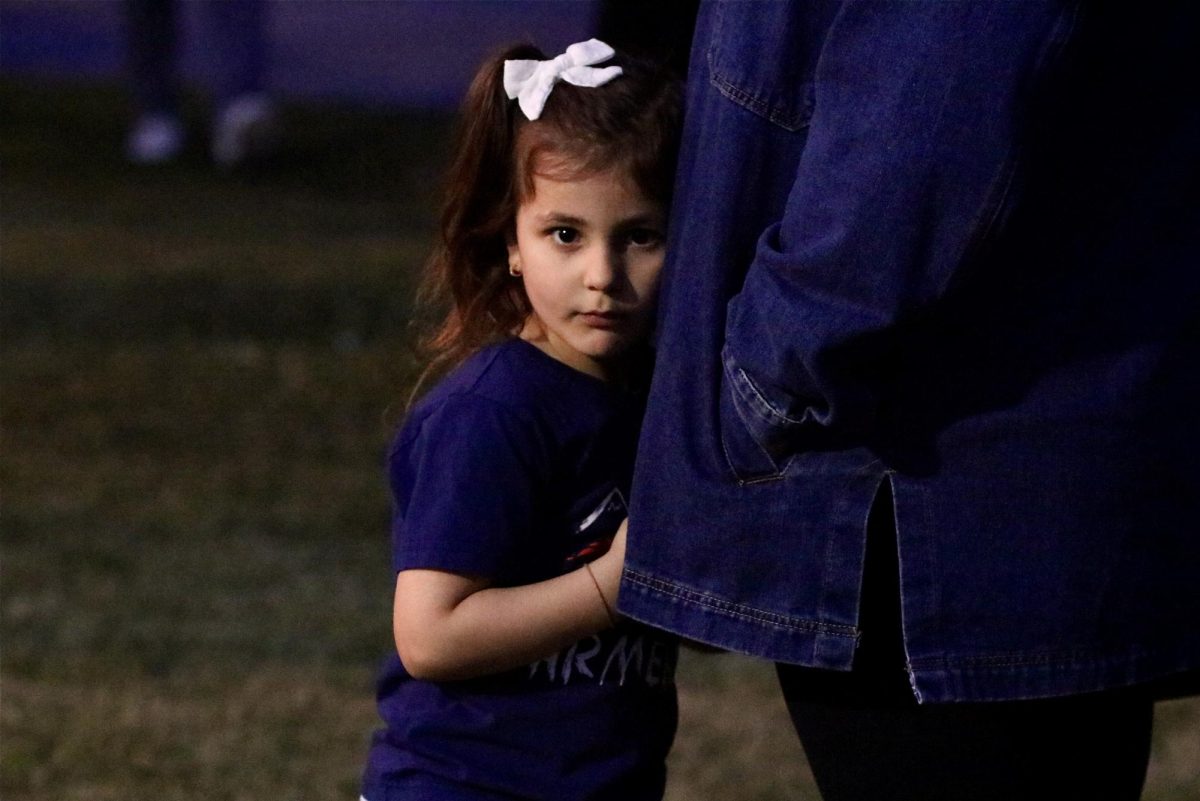A young girl looks at the camera while playing next to her mom.