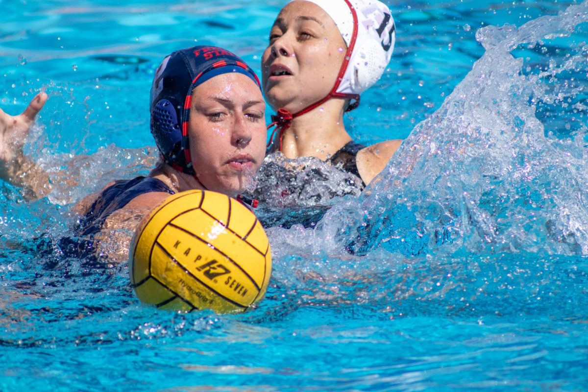 Fresno State water polo attacker Hailey Andress reaches for the ball while being pressured by a San Diego State Aztec defender on March 22 at the Fresno State Aquatics Center.