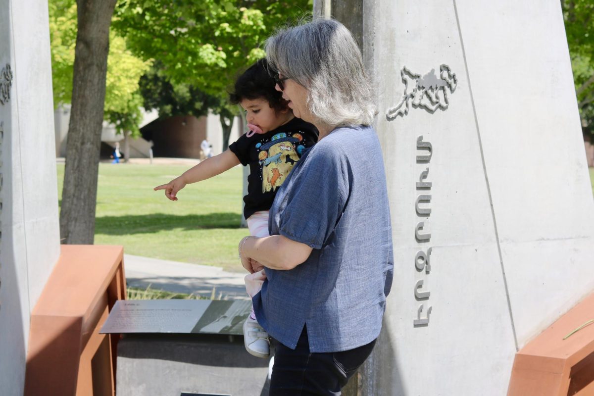 A woman holds a young child as she points at the flowers laid in the Armenian Genocide Monument. 